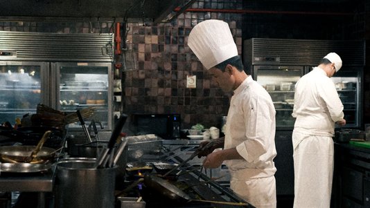 chefs cooking at stations in professional hotel kitchen