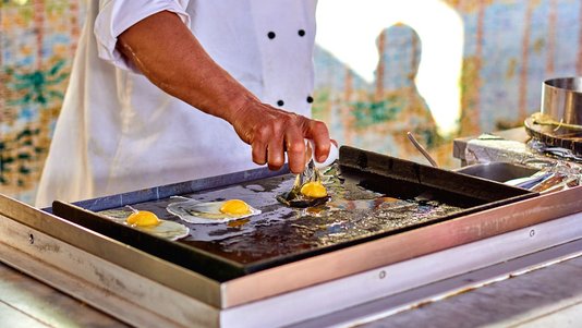 chef cooking eggs on commercial griddle at diner