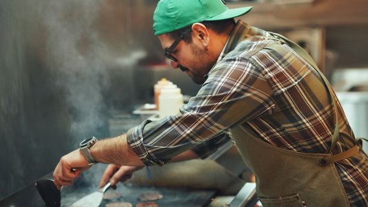 chef grilling burgers in fast food restaurant kitchen