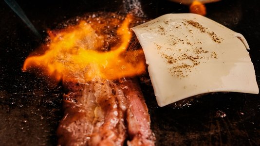 burger patties and cheese melting on commercial griddle