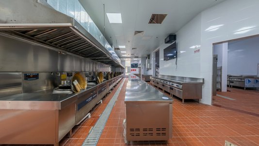 bright industrial kitchen with long stainless steel cooking lines