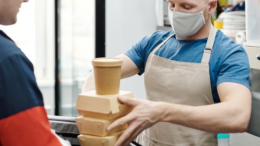 worker packing takeout orders in cloud kitchen