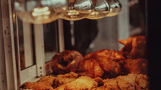 fried chicken display under heat lamps in shop front counter