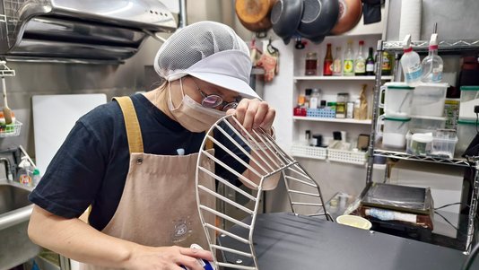 worker cleaning kitchen equipment with a spray in a professional kitchen