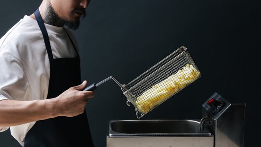 chef lifting a basket from a commercial deep fryer