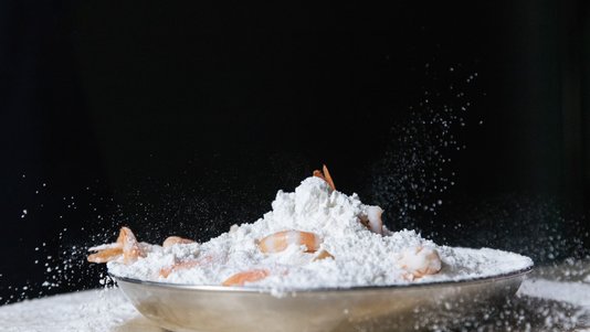 raw shrimp coated in flour in a stainless steel bowl