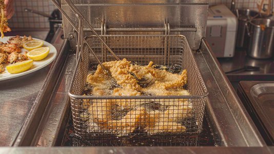 battered fish fillets frying in commercial open fryer